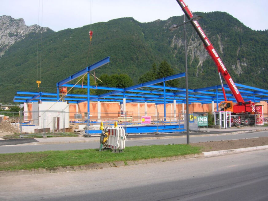 Baustelle mit blauer Stahlkonstruktion für den Neubau eines Einkaufscenters vor Bergkulisse