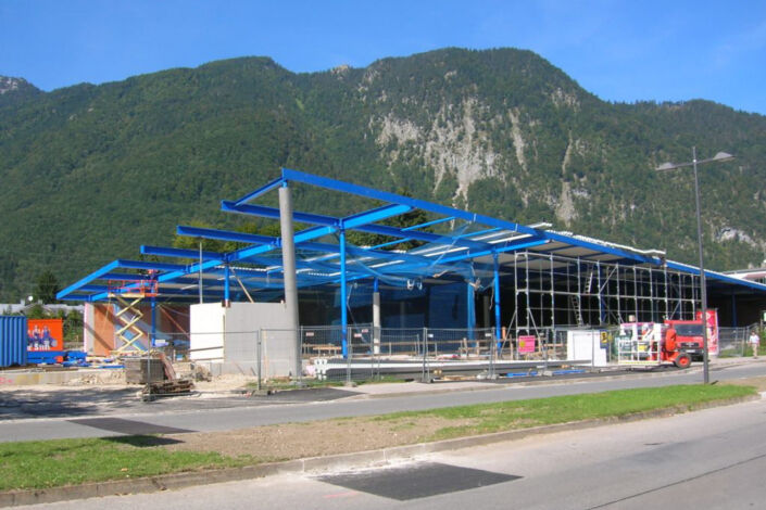 Neubau eines Einkaufscenters mit blauer Stahlkonstruktion und moderner Hallenstruktur