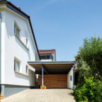 Moderner Carport mit Holzverkleidung und Schiebetür neben einem Einfamilienhaus