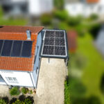 Luftbild eines Carports mit Photovoltaikanlage neben einem Wohnhaus