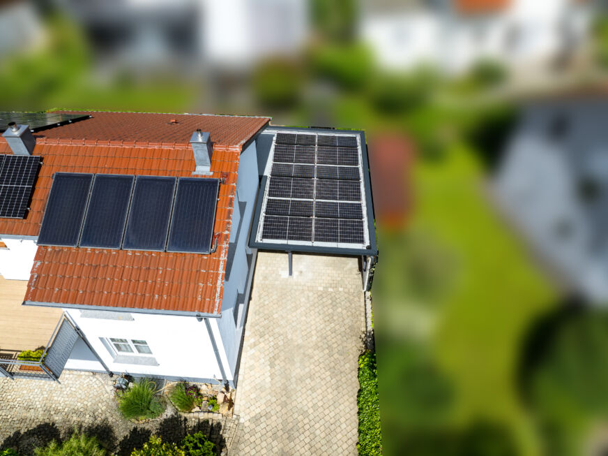 Luftbild eines Carports mit Photovoltaikanlage neben einem Wohnhaus