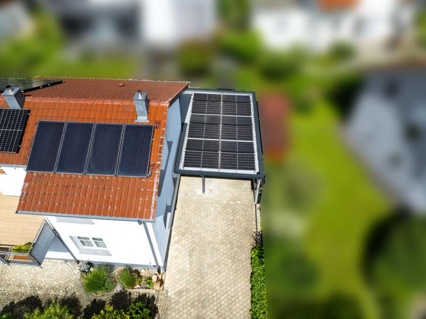 Luftbild eines Carports mit Photovoltaikanlage neben einem Wohnhaus