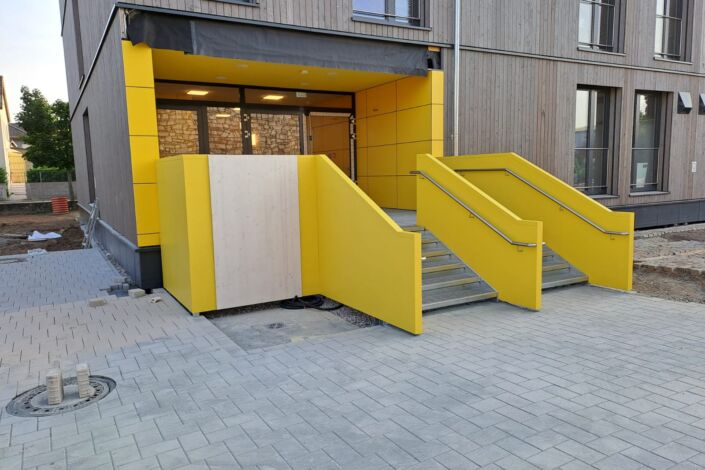 Zwei Außentreppen mit gelber Stahlblechverkleidung und montierten Edelstahlhandläufen
