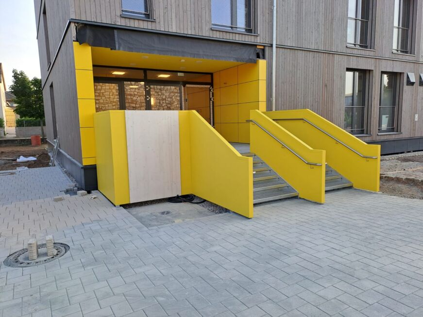 Zwei Außentreppen mit gelber Stahlblechverkleidung und montierten Edelstahlhandläufen