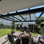 Ausblick unter einer Terrassenüberdachung mit Glasdach auf Garten mit Sitzbereich