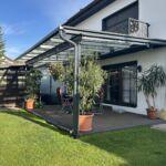 Komplettansicht einer modernen Terrassenüberdachung aus Glas und Stahl an einem Einfamilienhaus