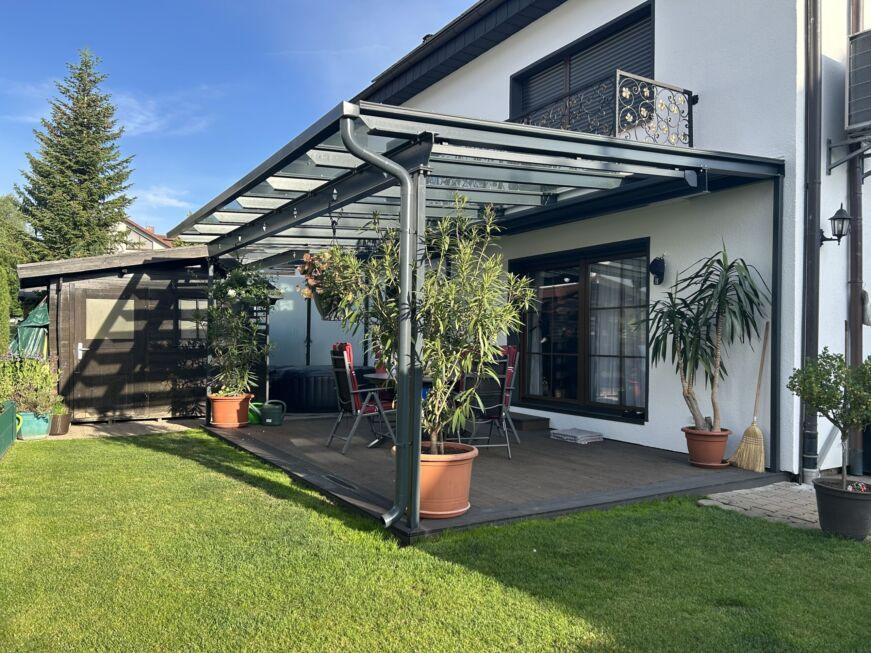 Komplettansicht einer modernen Terrassenüberdachung aus Glas und Stahl an einem Einfamilienhaus
