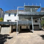 Dreistöckiger Balkonanbau mit verzinkter Stahlkonstruktion und grauen Aluminiumfüllungen an einem Bestandsgebäude