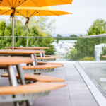 Runde Holztische mit gelben Sonnenschirmen auf der Dachterrasse der neuen Betriebskantine von Stahlbau Nägele