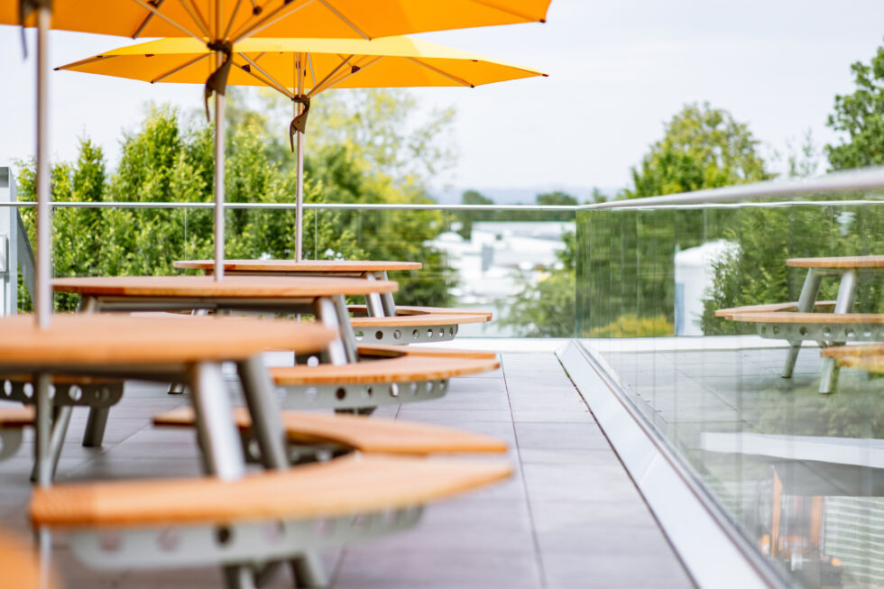 Runde Holztische mit gelben Sonnenschirmen auf der Dachterrasse der neuen Betriebskantine von Stahlbau Nägele