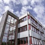 Detailaufnahme der Aufstockung mit rotem Fensterrahmen und Stahl-Verbindungsbau