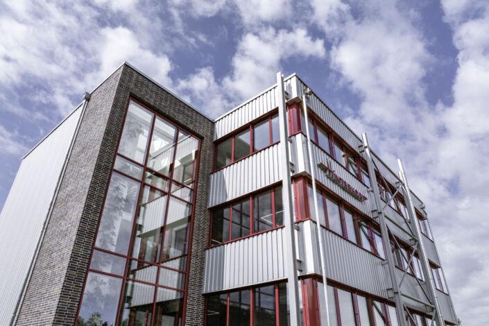 Detailaufnahme der Aufstockung mit rotem Fensterrahmen und Stahl-Verbindungsbau