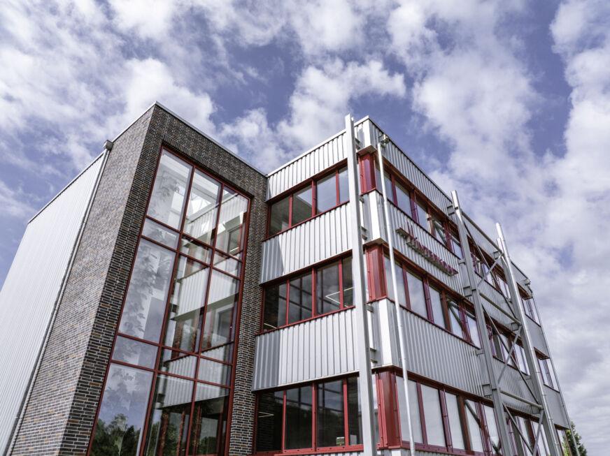 Detailaufnahme der Aufstockung mit rotem Fensterrahmen und Stahl-Verbindungsbau