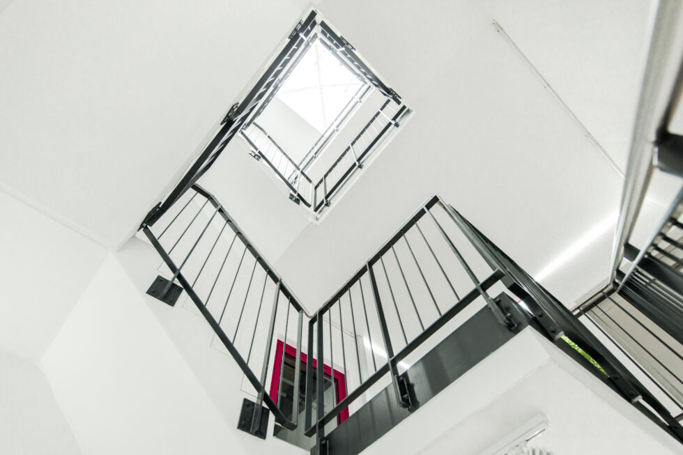 Blick nach oben durch das moderne Treppenhaus mit Stahlgeländer und Oberlicht