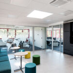 Moderner Lounge-Bereich mit Sitzgelegenheiten, Küchenzeile und Weltkarte an der Glaswand
