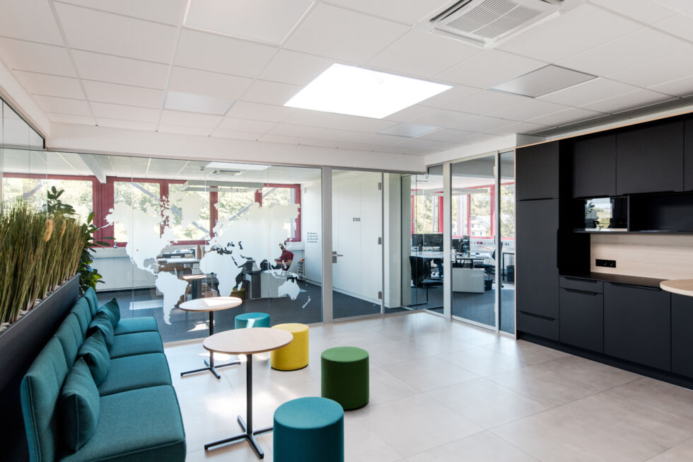 Moderner Lounge-Bereich mit Sitzgelegenheiten, Küchenzeile und Weltkarte an der Glaswand