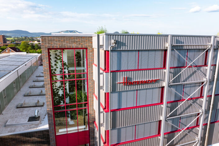 Glasverbindungsbau mit rotem Fensterrahmen und reflektierender Glasfassade