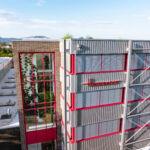 Glasverbindungsbau mit rotem Fensterrahmen und reflektierender Glasfassade