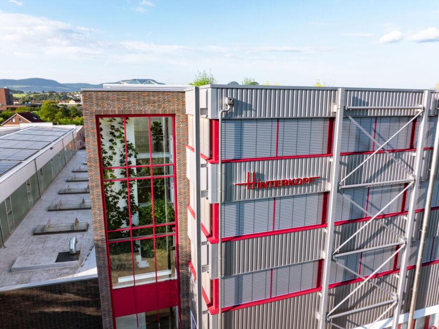 Glasverbindungsbau mit rotem Fensterrahmen und reflektierender Glasfassade