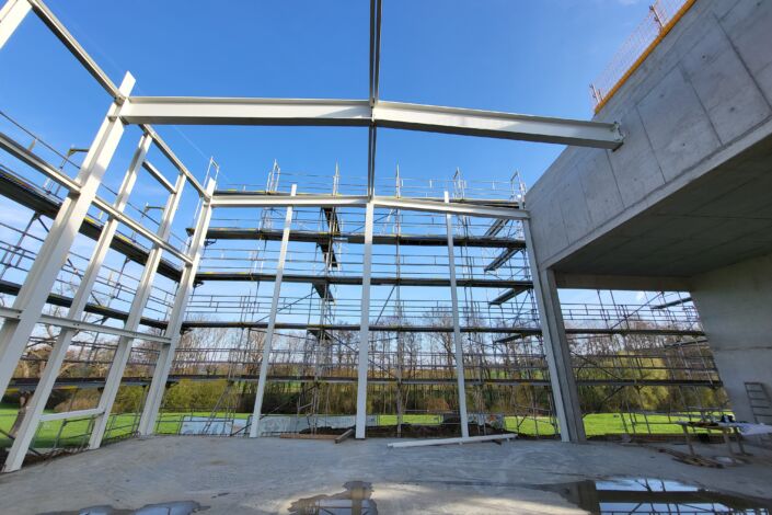 Innenansicht einer Stahlhalle mit beschichteten Stahlträgern und Baugerüsten