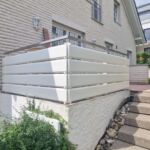 Weiße Terrassenbrüstung aus horizontalen Profilen mit Edelstahlhandlauf
