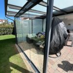 Seitenansicht der nachgerüsteten Glas-Schiebewand unter einer modernen Terrassenüberdachung