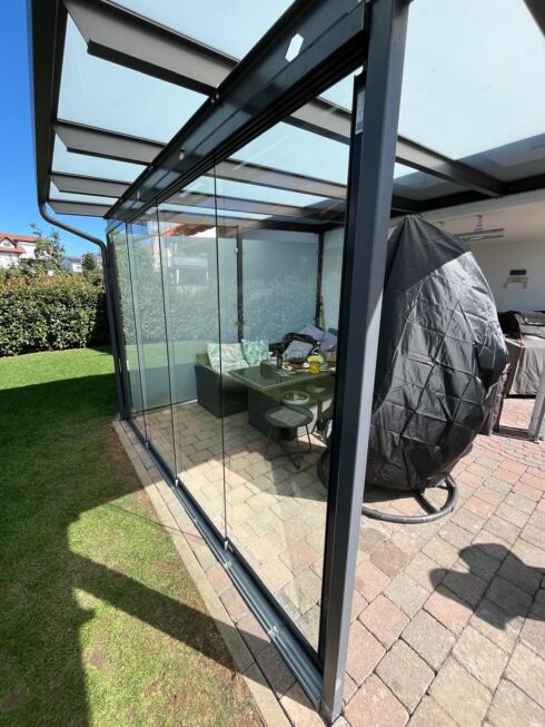 Seitenansicht der nachgerüsteten Glas-Schiebewand unter einer modernen Terrassenüberdachung