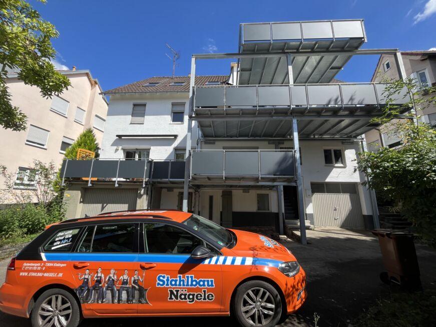 Dreigeschossiger Balkonanbau mit Stahlkonstruktion und Stahlbau Nägele Fahrzeug im Vordergrund