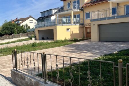 Pulverbeschichtete Zaunanlage mit Zierelementen auf gemauerter Brüstung vor Wohnhaus