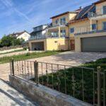 Pulverbeschichtete Zaunanlage mit Zierelementen auf gemauerter Brüstung vor Wohnhaus