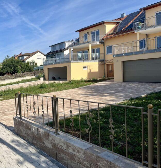 Pulverbeschichtete Zaunanlage mit Zierelementen auf gemauerter Brüstung vor Wohnhaus