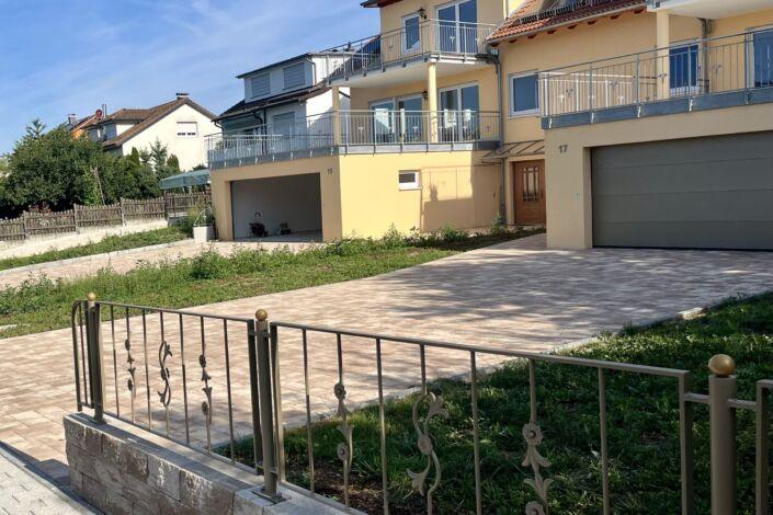 Pulverbeschichtete Zaunanlage mit Zierelementen auf gemauerter Brüstung vor Wohnhaus