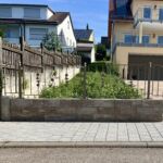 Detailaufnahme eines Zaunfeldes mit Zierstäben und Kugelpfosten auf gemauerter Brüstungsmauer