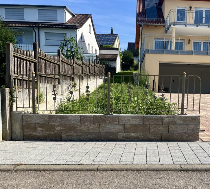 Detailaufnahme eines Zaunfeldes mit Zierstäben und Kugelpfosten auf gemauerter Brüstungsmauer