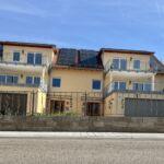 Frontalansicht einer Zaunanlage mit Zierelementen und Kugelpfosten auf gemauerter Mauer vor Mehrfamilienhaus