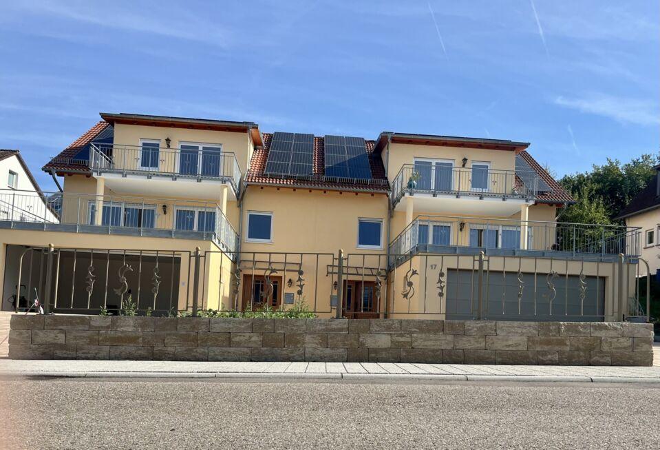 Frontalansicht einer Zaunanlage mit Zierelementen und Kugelpfosten auf gemauerter Mauer vor Mehrfamilienhaus