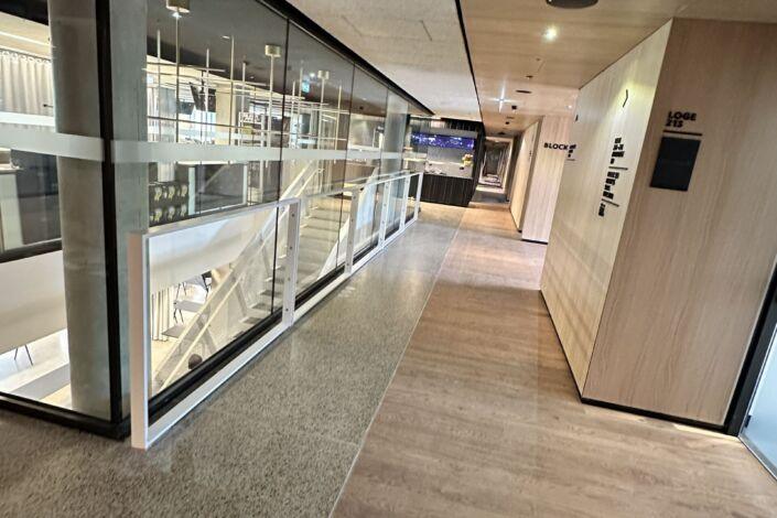 Innenflur der MHP-Arena mit Glasgeländer, Holzverkleidung und moderner Lichtführung