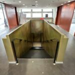 Treppenabgang mit pulverbeschichteten Handläufen und goldfarbener Wandverkleidung in der MHP-Arena
