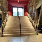 Breite Treppe mit mittigem und seitlichem Handlauf sowie gelochten Metallpaneelen in der MHP-Arena Stuttgart