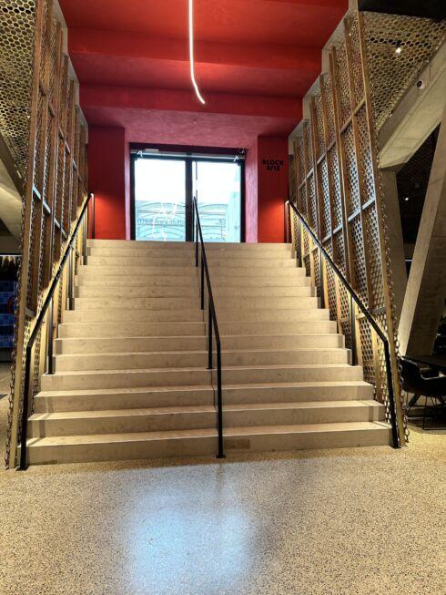 Breite Treppe mit mittigem und seitlichem Handlauf sowie gelochten Metallpaneelen in der MHP-Arena Stuttgart