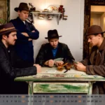 Tableau vivant Die Kartenspieler, drei Männer mit Hüten sitzen an kleinem Tisch und spielen Karten, ein vierter Mann steht dahinter mit verschränkten Armen