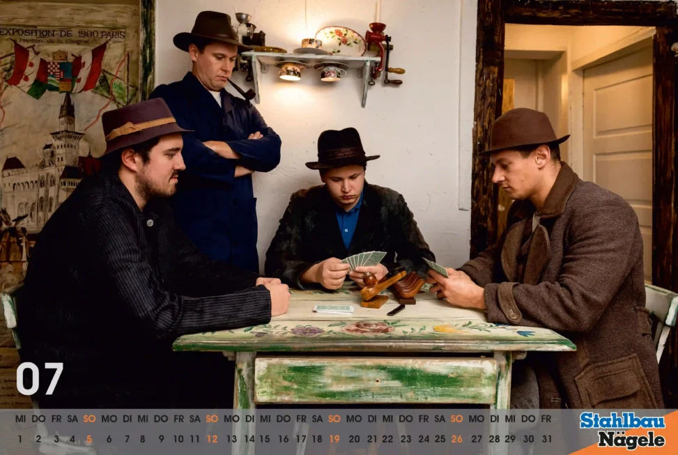 Tableau vivant Die Kartenspieler, drei Männer mit Hüten sitzen an kleinem Tisch und spielen Karten, ein vierter Mann steht dahinter mit verschränkten Armen