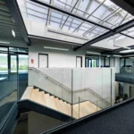 Galerie mit Glasgeländer und Stahltreppe im Bürobereich eines Lagergebäudes