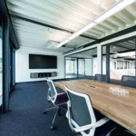 Moderner Besprechungsraum im Bürogebäude eines Lagerneubaus mit Glaswänden und sichtbarer Stahlkonstruktion