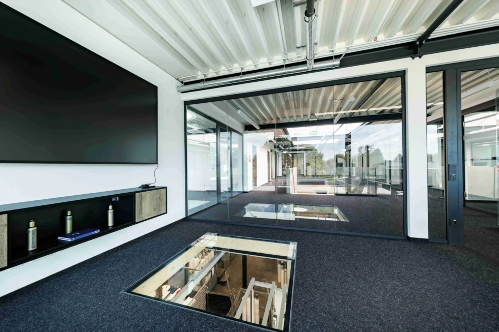 Galerieflur mit Glaswänden und Blick auf die Stahltreppe im Bürogebäude eines Lagerneubaus