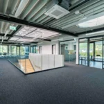 Offene Galerie mit Glasgeländer und Stahltreppe im Bürobereich eines modernen Lagergebäudes