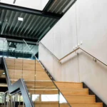 Stahltreppe mit Glasgeländer und Holzstufen im Bürobereich eines Lagerneubaus