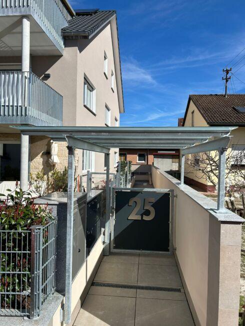 Stahl Überdachung mit Glas über Eingangsbereich und Briefkastenanlage eines Wohnhauses