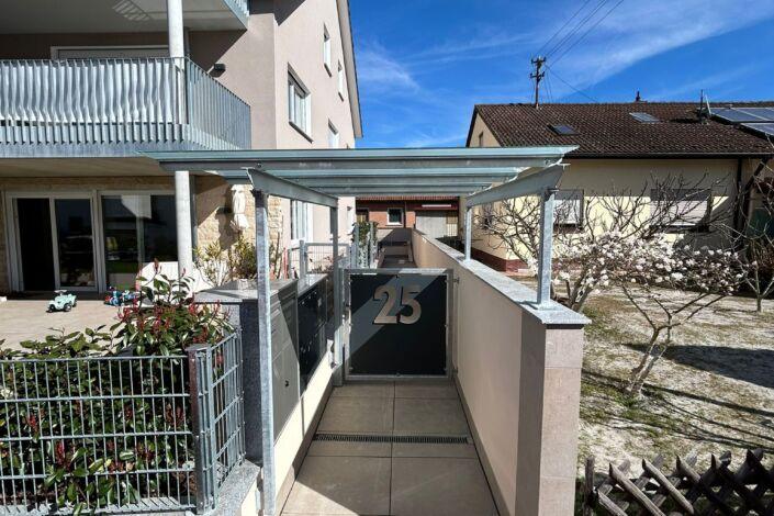 Stahl Überdachung mit Glas über Eingangsbereich und Briefkastenanlage eines Wohnhauses