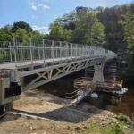 Moderne Stahlbrücke mit Fachwerkkonstruktion, Geländern und Flussquerung